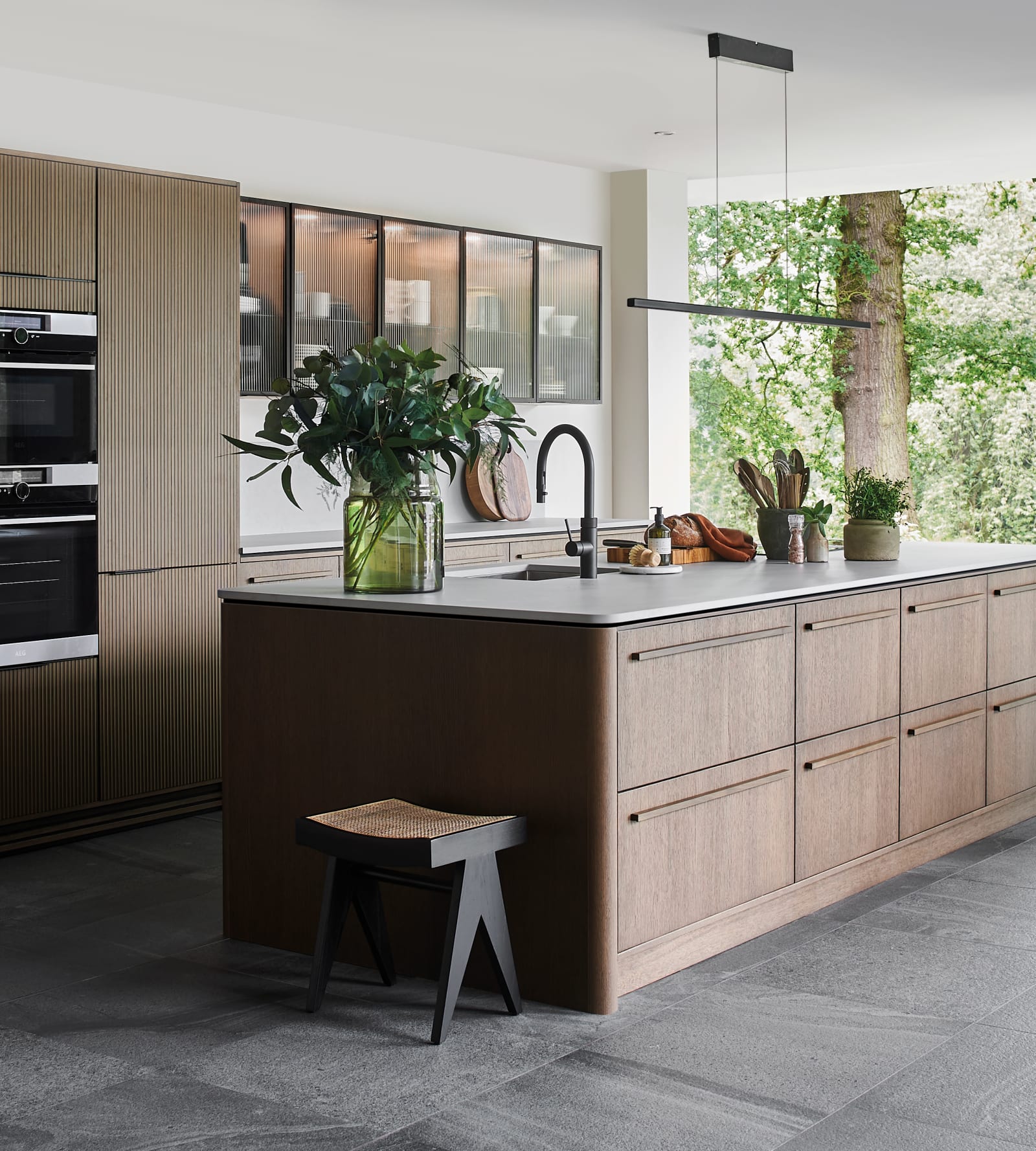 Magnet Kitchens 2021 Nordic Nature range with Fluted oak doors and Integra Hoxton Pebble cabinets with Dekton Aeri worktop. U-shaped kitchen with breakfast bar area.