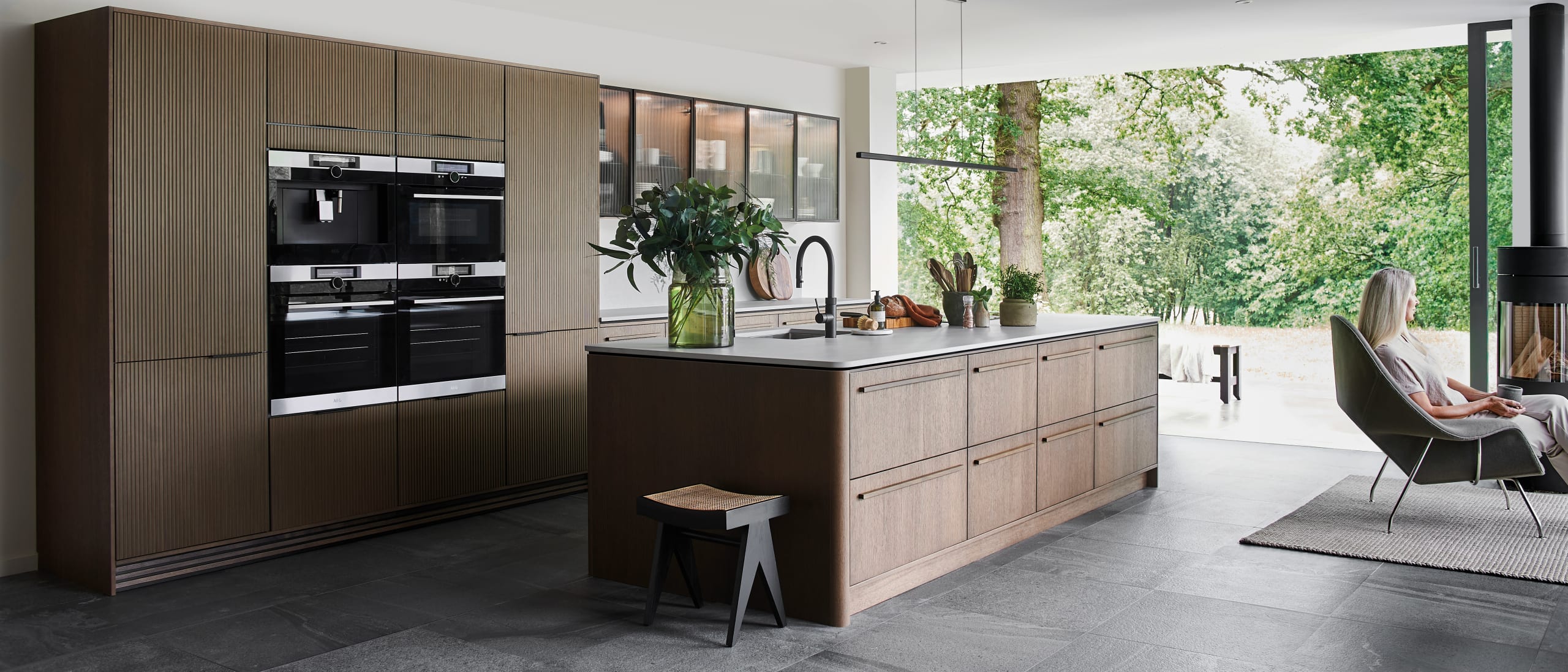 Magnet Kitchens 2021 Nordic Nature range with Fluted oak doors and Integra Hoxton Pebble cabinets with Dekton Aeri worktop. U-shaped kitchen with breakfast bar area.